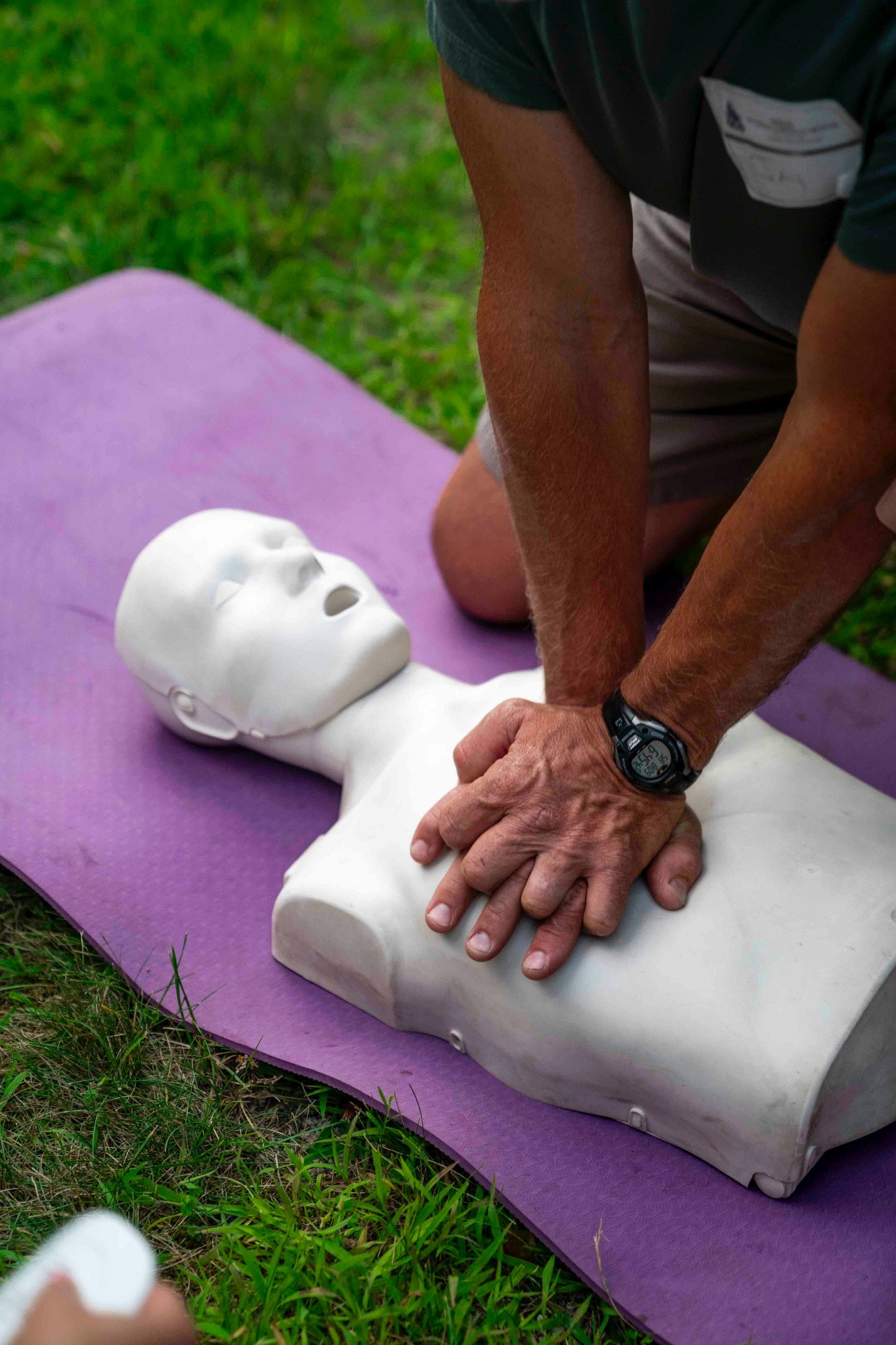 Hands performing CPR compressions on a training mannequin